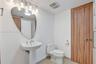 Pedestal sink featuring a curved mirror, wood-finish door, four-light vanity fixture, and tile flooring