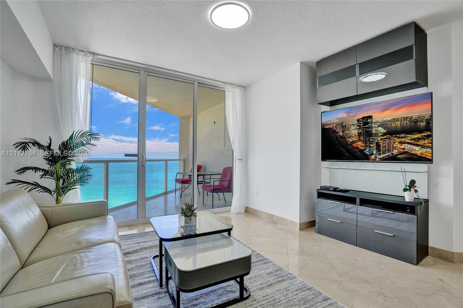 Floor-to-ceiling glass doors, expansive private balcony, polished stone flooring, and built-in high-gloss cabinetry