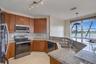 Kitchen featuring wood cabinetry, stone-surface countertops, stainless steel appliances, a double-basin undermount sink, and large windows