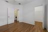 Room with wood-finish flooring, white walls, and a walk-in closet featuring wire shelving