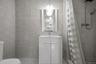 Bathroom featuring full-height neutral wall tiling, vanity with a white integrated sink, polished chrome faucet, wall-mounted globe lighting fixture, 