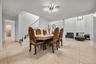 Large-format ceramic tile flooring, modern multi-arm linear ceiling fixture, and open staircase with white balusters