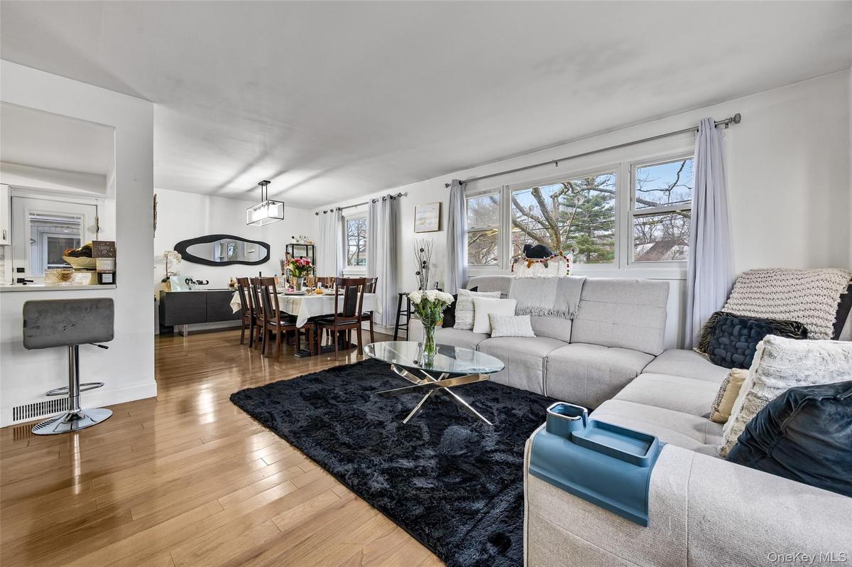 Open-concept living and dining area featuring wood-finish flooring, recessed lighting, expansive windows, and a built-in breakfast bar