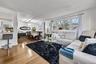 Open-concept living and dining area featuring wood-finish flooring, recessed lighting, expansive windows, and a built-in breakfast bar