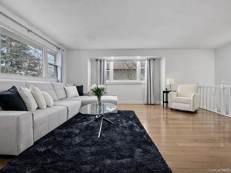 Spacious room featuring wood-finish flooring, multi-pane windows, recessed lighting, and a white balustrade railing