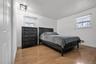 Room featuring wood-finish flooring, two windows with adjustable shades, and a geometric metal-frame ceiling light fixture