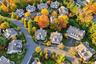 Aerial perspective of a residential neighborhood featuring paved asphalt roadways, multi-story residences with shingled roofing, paved driveways, and 
