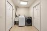 Laundry area featuring a utility sink, built-in appliance hookups, overhead lighting, and two six-panel doors set over tiled flooring