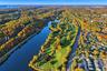 Aerial perspective of a golf course featuring manicured fairways, integrated water features, and expansive mature greenery