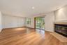 Spacious living area featuring wood-finish flooring, recessed lighting, a tile-surround fireplace, and sliding glass doors