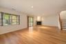 Open-concept interior featuring wood-finish flooring, a corner fireplace with a stone-surround mantel, recessed lighting, expansive multi-pane windows