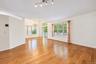 Open-concept interior featuring wood-finish flooring, multi-pane windows, vaulted ceilings, a multi-light track fixture, and a decorative chandelier