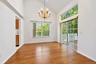 Vaulted ceiling featuring a classic tiered chandelier, wood-finish flooring, and expansive glass sliding doors with overhead transom windows