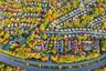 Aerial perspective of a residential community featuring mature deciduous trees, a tennis court, a swimming pool, and a winding internal road network