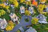 Aerial perspective of a suburban neighborhood featuring multi-story residences, asphalt cul-de-sac, expansive manicured lawns, and mature deciduous tr