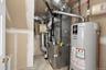Mechanical utility closet housing a high-efficiency furnace, metal ductwork, and a vertical water heater with copper piping