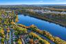 Aerial perspective featuring a waterfront setting, mature foliage, and a metropolitan skyline in the distance