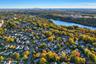 Aerial perspective of the residential area featuring dense tree canopy, proximity to a body of water, and a distant city skyline