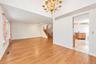 Interior featuring wood-finish flooring, vaulted ceilings, a prominent brass multi-arm chandelier, and a wood-railing staircase
