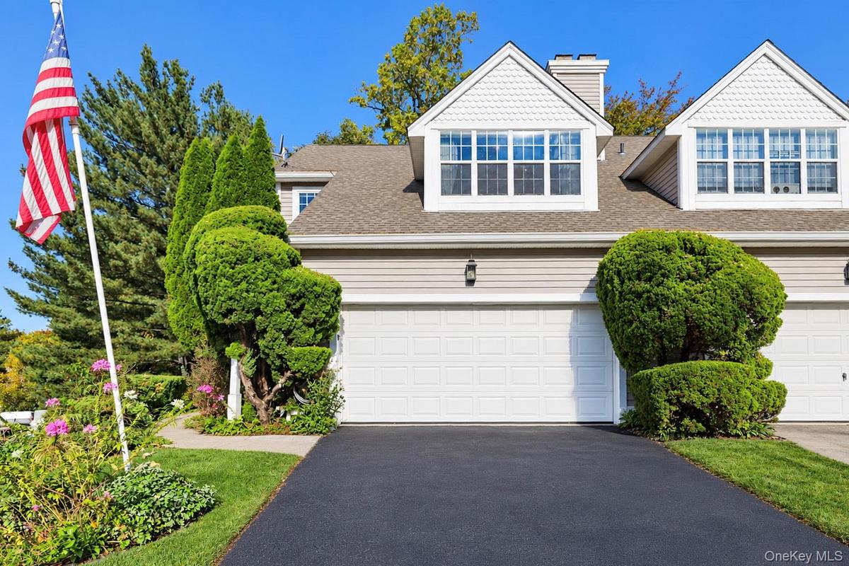 Exterior facade featuring horizontal siding, dual gables with shingle accents, multi-pane windows, and a paved private driveway