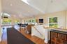 Open-concept living space featuring vaulted ceilings, recessed lighting, wood-finish flooring, and multiple sliding glass doors