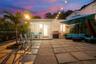 Private patio featuring large-format concrete pavers, perimeter hedge landscaping, and an integrated built-in grill area