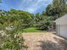 Paver driveway, manicured lawn, established landscaping, and attached garage
