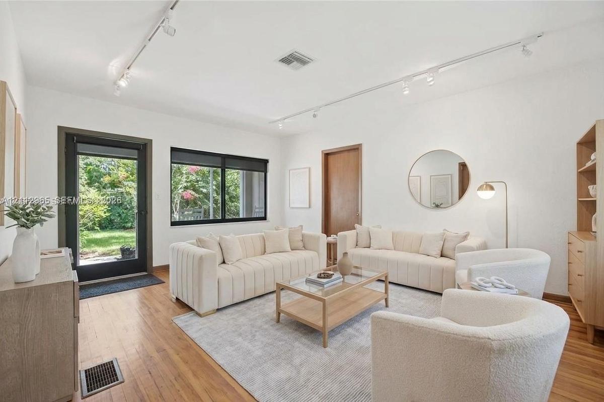 Living space featuring wood-finish flooring, track lighting, and a glass-panel exterior door with metal frame