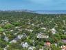 Aerial perspective of 4152 Battersea Rd, featuring dense mature tree canopy, proximity to the coastline, and urban skyline backdrop