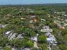Aerial perspective of residential property featuring a paved driveway, mature canopy trees, and dense professional landscaping