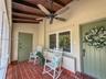 Covered porch featuring terracotta tile flooring, exposed wood-beam ceiling, and a multi-blade ceiling fan