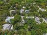 Aerial perspective of a property lot characterized by mature tree canopy and abundant vegetation within a suburban setting