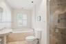 Bathroom featuring a pedestal sink, soaking tub with tile surround, glass-enclosed shower with metallic fixtures, and plantation shutters