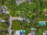 Aerial perspective featuring mature tree canopy, paver driveway, and roof-mounted solar panels