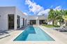 Modern exterior with smooth stucco finish, rectangular swimming pool with stone coping, concrete patio, covered outdoor area, and established palm tre