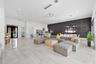 Open-concept living space featuring high ceilings with recessed lighting, large-format tile flooring, a charcoal stone-finish accent wall, and contemp
