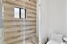 Walk-in shower featuring wood-finish tile wall cladding, frameless glass enclosure, wall-mounted shower fixture, and a built-in window, paired with a 