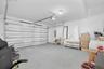 Two-car garage featuring a sectional overhead door, painted concrete flooring, and ceiling-mounted light fixture