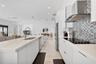 Kitchen featuring flat-panel white cabinetry, quartz countertops, a mosaic tile backsplash, a stainless steel range hood, and large-format tile floori