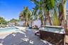 Outdoor area featuring a swimming pool, wood-finish decking, an integrated spa, and mature tropical landscaping