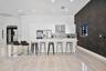 Modern kitchen featuring flat-panel white cabinetry, a waterfall-edge kitchen island, stone-finish tile flooring, a mosaic tile backsplash, and a dark