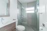 Bathroom featuring a wood-finish vanity with a rectangular basin, glass-enclosed shower with large-format tile surround, integrated shower head system