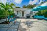 Enclosed patio featuring large-format concrete pavers, gravel infill, ornamental metal porch supports, and mature palm tree landscaping
