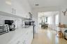 Kitchen featuring white flat-panel cabinetry, light-toned stone-surface countertops, a double-basin stainless steel sink with gooseneck faucet, white 