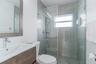 Bathroom featuring a wood-finish floating vanity, integrated sink with chrome faucet, framed mirror, and a walk-in shower enclosed by glass paneling w