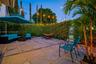 Backyard patio featuring concrete pavers, aggregate stone detailing, and a perimeter hedge enclosure