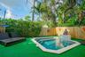 Backyard area featuring an in-ground swimming pool, stone-tile coping, integrated water feature with patterned inlay, wood privacy fencing, and overhe