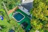 Backyard featuring an in-ground pool with stone coping, synthetic turf surfacing, wood-plank fencing, and mature trees