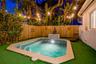 In-ground pool featuring a stone-paver coping, tile-accented water feature, and integrated steps, enclosed by a wood privacy fence