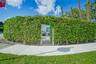 Exterior grounds featuring a tall privacy hedge, gated metal entrance, and paved walkway